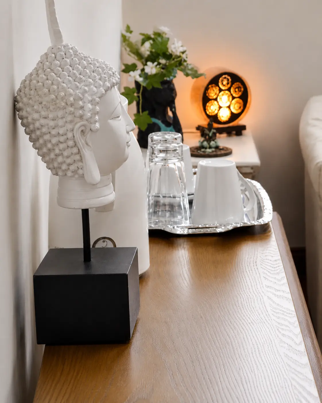 Detalle decorativo de sala de terapia con figura blanca, bandeja de agua y luz cálida